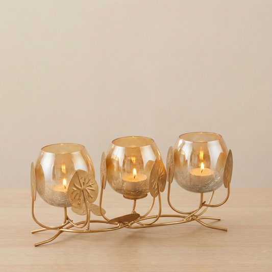 Decorative candle holder with three lit candles on a wooden surface.