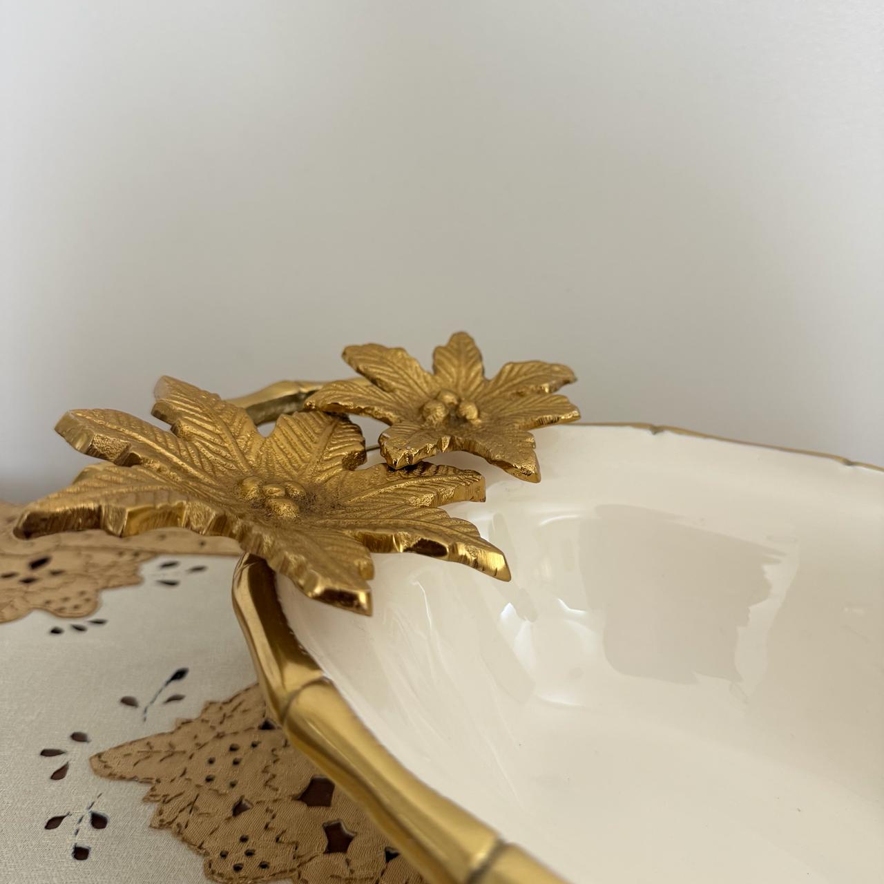 Decorative white dish with gold floral embellishments on a plain background