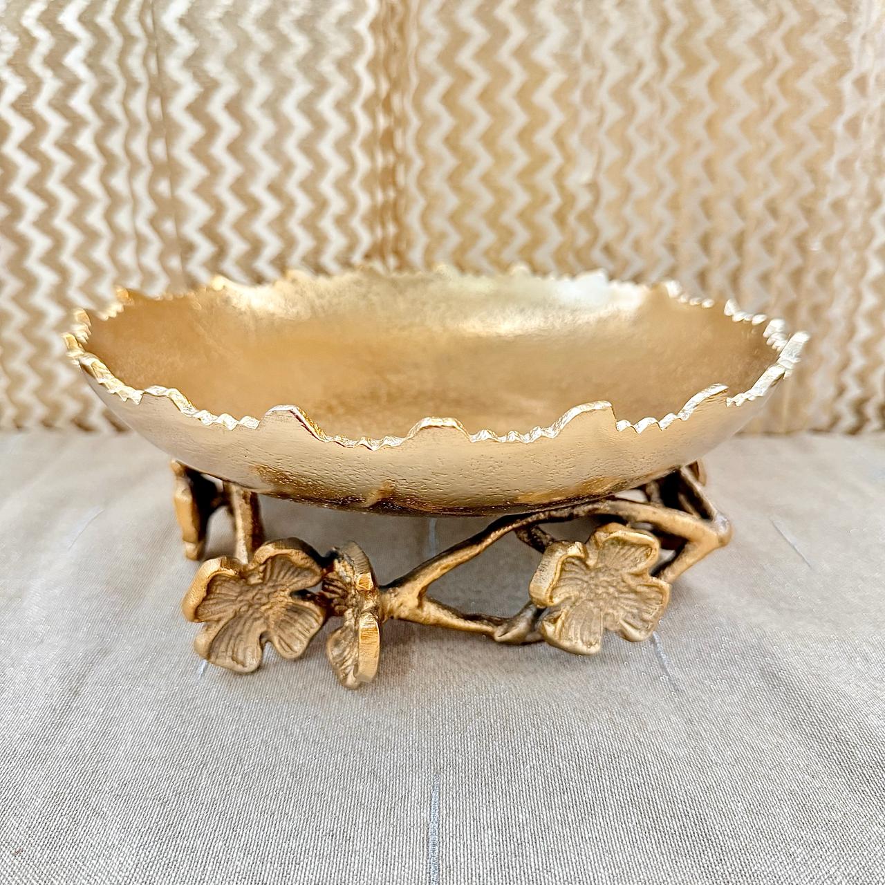 Gold decorative bowl with floral base on a textured surface