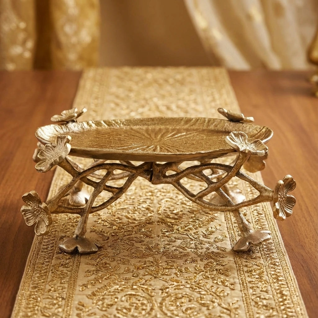 Decorative gold metal tray with floral designs on a wooden surface
