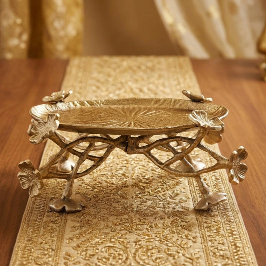 Decorative gold metal tray with floral designs on a wooden surface