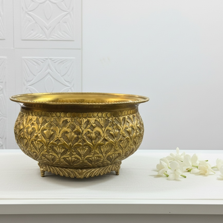 Decorative brass table bowl on a white surface with a white textured wall background
