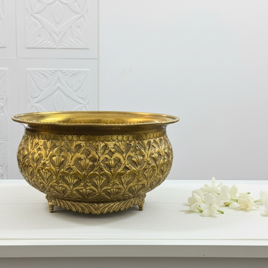 Decorative brass table bowl on a white surface with a white textured wall background
