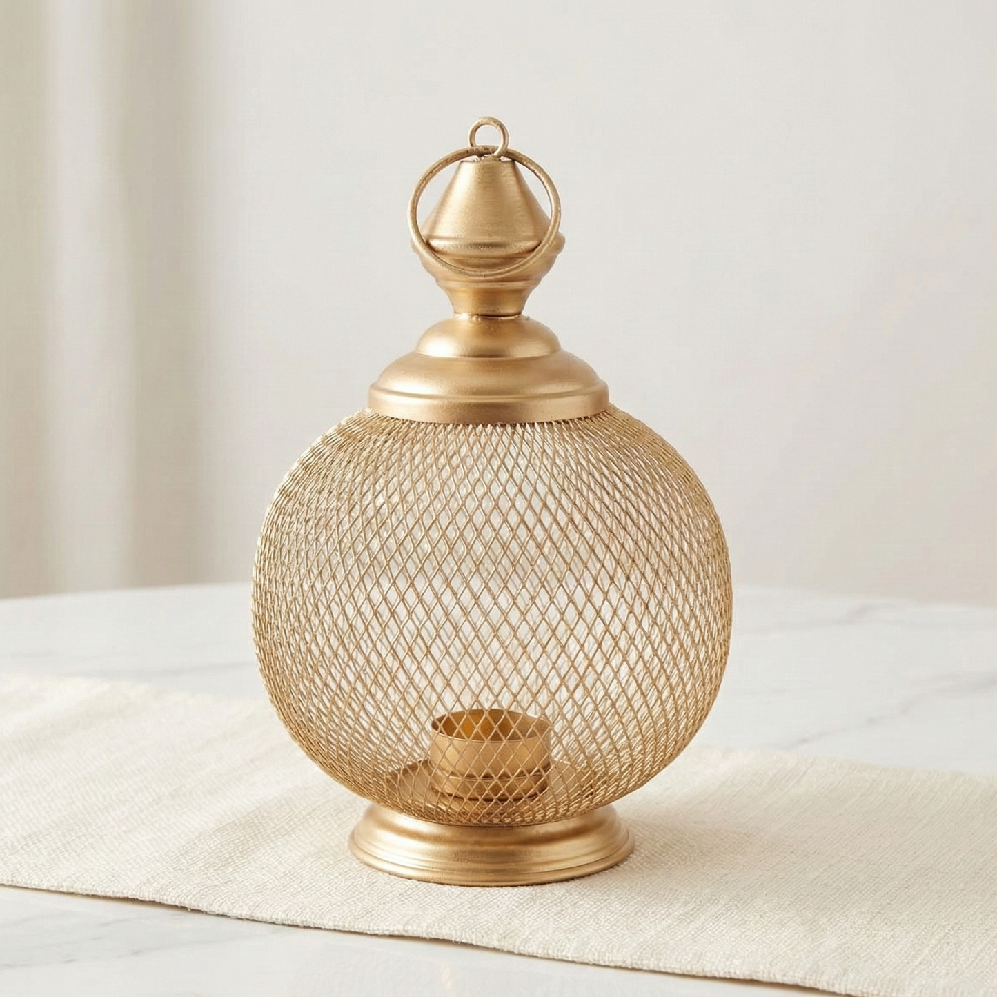 Gold mesh lantern on a white surface with a neutral background